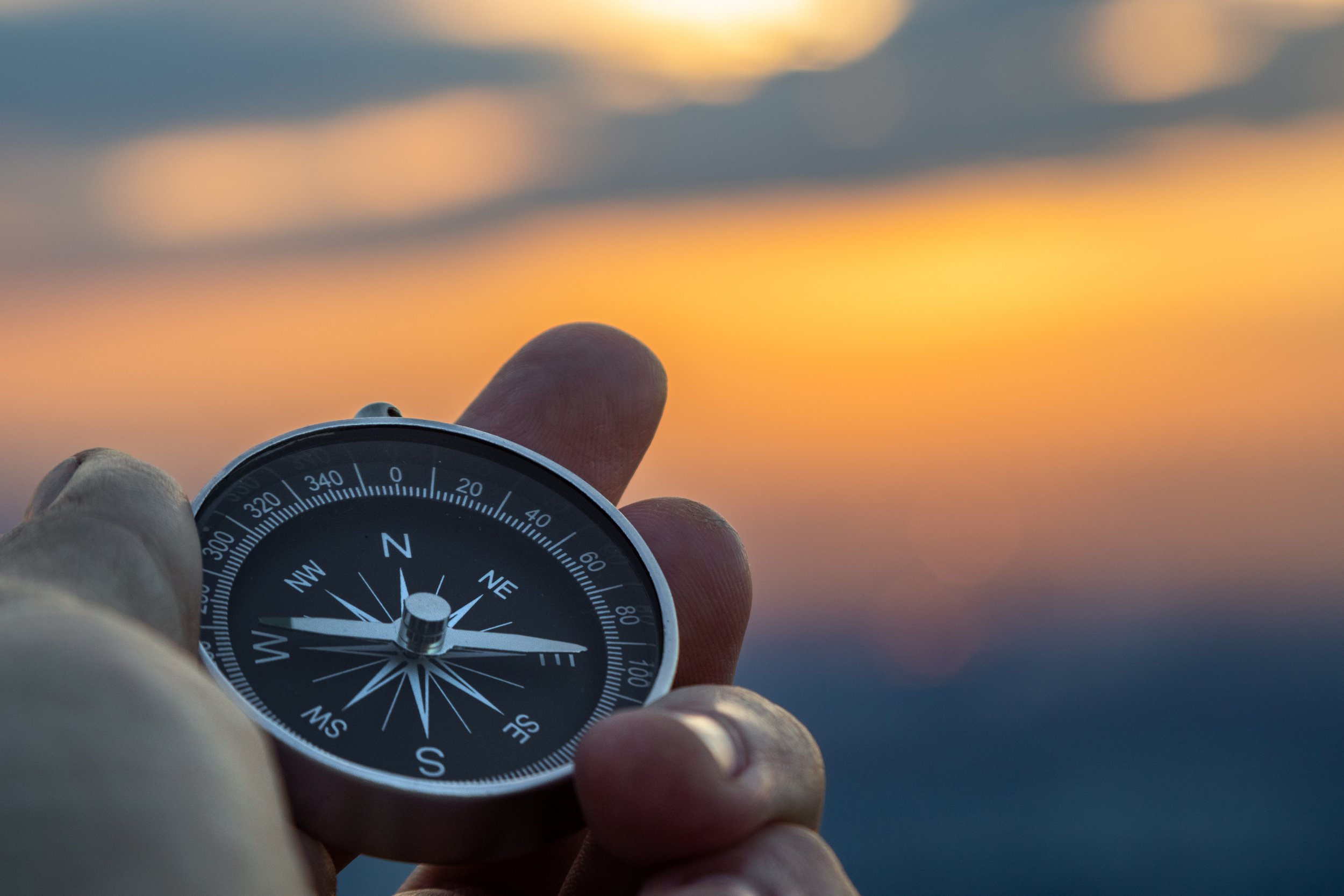 Kompass in der Hand vor Sonnenuntergang